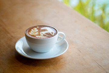 A cup of latte coffee decorated with milk in the shape of a horse is placed on a table in a coffee shop. with space for text input