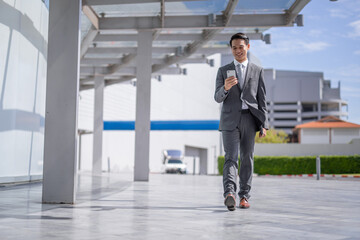 Businessman with smartphone walking against street blurred building background, Fashion business...