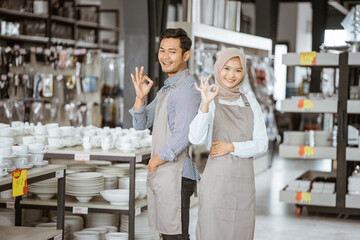 two shop assistants standing with okay hand gesture in houseware store