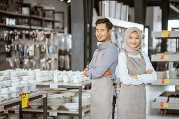 Shop assistant boy and girl in veil standing smiling for camera in houseware store