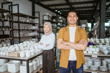 Handsome asian man smiling while standing with arms crossed in houseware store