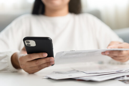 Woman holding paper bill invoice and mobile phone