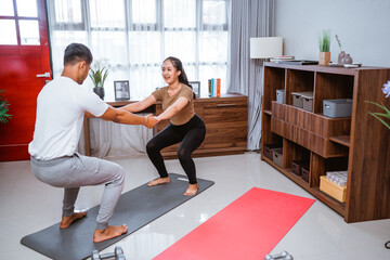 Fototapeta na wymiar portrait of young asian couple workout together at home stretching their body