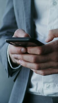 A young man in a business suit, is typing on a mobile phone, close-up