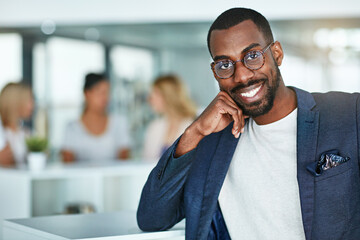 Confident, happy and smiling creative man standing in the office with a team of marketing agents in background. Portrait of cheerful, motivated and proud designer ready for success in startup company