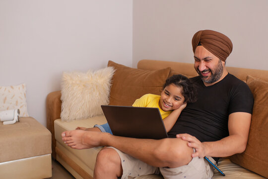 Father and daughter watching cartoons on laptop in living room