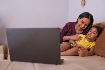 Mother and daughter watching cartoons on laptop in living room