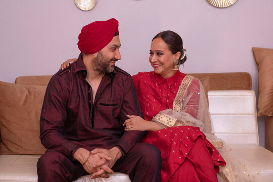 Portrait of a happy Sikh couple sitting together on sofa in living room