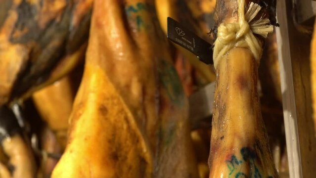 Leg of Iberian ham detailed macro shoot moving, where it is seen in the reflections of light on the black brown skin of the Iberian pig .the curator touches and test the leg where details are shown 