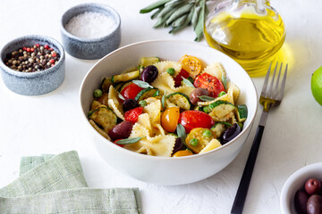 Pasta farfalle with tomatoes, zucchini, peas, Kalamata olives and sage. Healthy eating. Vegetarian food.