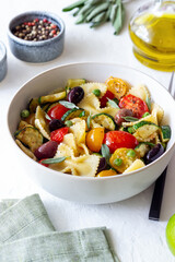 Pasta farfalle with tomatoes, zucchini, peas, Kalamata olives and sage. Healthy eating. Vegetarian food.