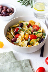 Pasta farfalle with tomatoes, zucchini, peas, Kalamata olives and sage. Healthy eating. Vegetarian food.