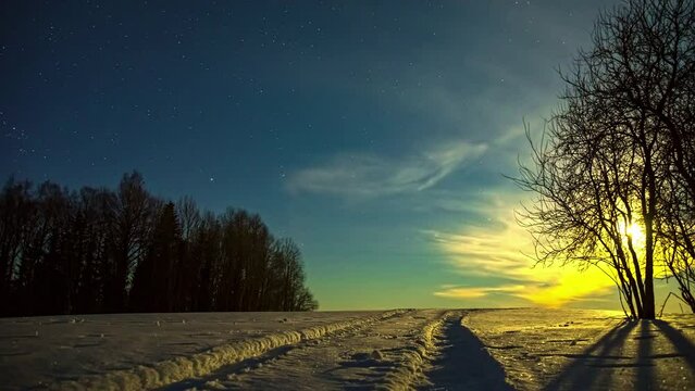 Timelapse shot of car tracks on white snow covered during winter season with the view of sun rising over the background through Cirrostratus clouds at daytime.