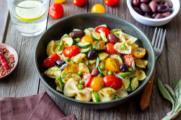 Pasta farfalle with tomatoes, zucchini, peas, Kalamata olives and sage. Healthy eating. Vegetarian food.