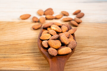 Almonds in a wooden spoon on the table.