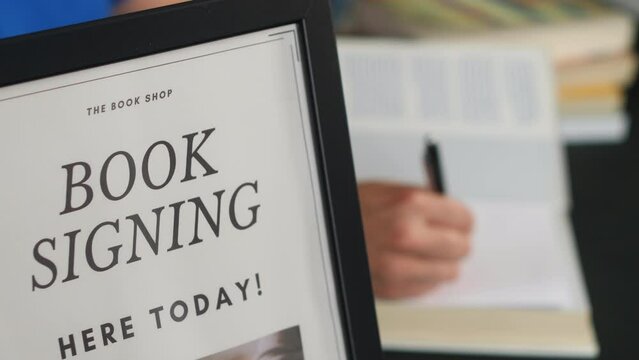 Side view of an unrecognizable author signing books at a book launch