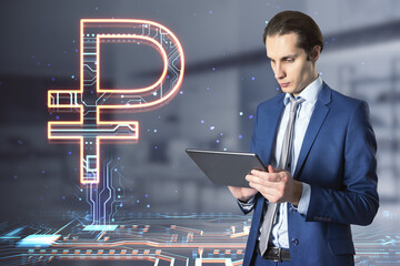 Attractive european businessman holding tablet with creative glowing Russian ruble hologram on blurry office interior background. Digital money and online banking concept. Double exposure.