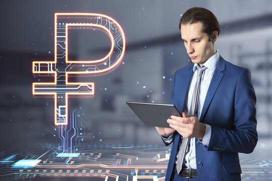 Attractive european businessman holding tablet with creative glowing Russian ruble hologram on blurry office interior background. Digital money and online banking concept. Double exposure.