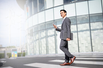 Businessman with smartphone walking against street blurred building background, Fashion business photo of beautiful girl in casual suite with smart phone. © lifepic