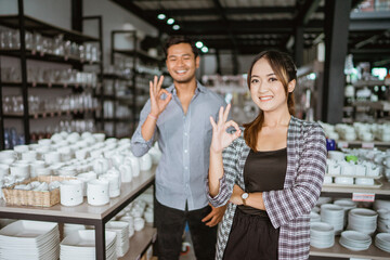 Beautiful asian woman smiling while standing with okay hand gesture in houseware store