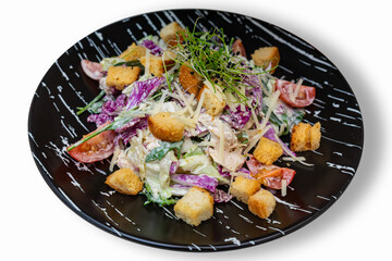 Salad of meat, croutons and vegetables. Black plate with salad on a white background. Isolate
