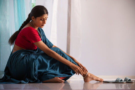 Woman model tying silver anklet on her feet