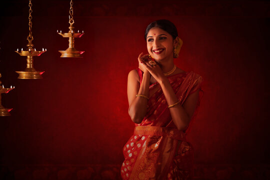 Portrait of a cheerful woman in traditional outfit standing near oil lamps on the occasion of Diwali