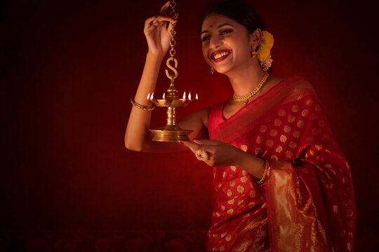 Woman in traditional outfit lighting oil lamp on the occasion of Diwali