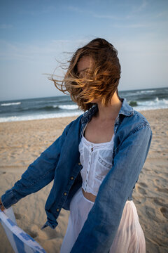 Windblown hair on woman in white see through dress on beach in Hamptons