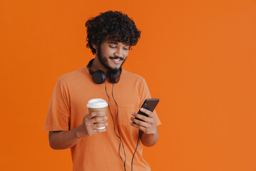 Young indian smiling man with headphones ,phone and coffee