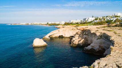 Aerial bird's eye view of coastline landmark ‘Love bridge’ and sea caves at Cavo Greco, Ayia Napa, Famagusta, Cyprus from above. A tourist attraction cliff rock natural formation arch in Ammochostos. 