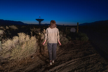 a person appears to be abucted by aliens in a sci-fi looking scene near radio astronomy telescope