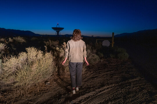 a person appears to be abucted by aliens in a sci-fi looking scene near radio astronomy telescope