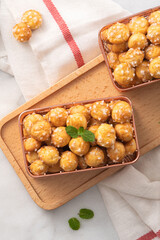 Delicious French Chouquette Choux Pastry dessert Pearl Sugar Puff on white marble background.