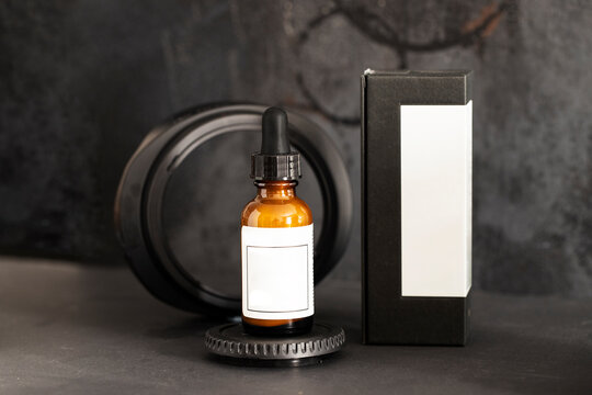 Amber glass dropper bottle with  pipet on a circle podium on a black background. Mock up Cosmetic image background.