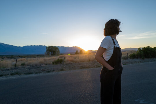 Young woman gazes into distance in desert landscape as last light of sunset descends