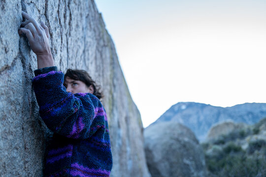Rock climber intensely crimps hold in Buttermilk boulders, Bishop, CA