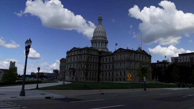 Michigan state capitol building in Lansing, Michigan with ground level time lapse video showing fast moving clouds with zoom in.