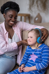 African american woman putting headphones on a girls head
