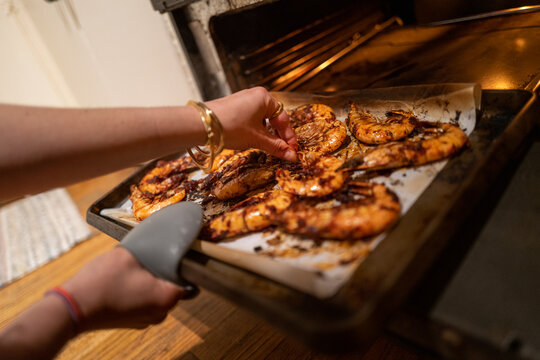 Home chef checks oven roasted jumbo prawn shrimps covered in spices