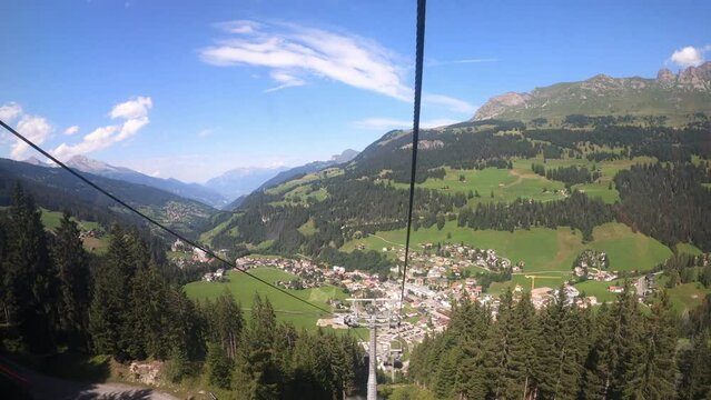 Cable car ride in the canton of Grisons. The gondola lift descends into the valley. You can see the small village in the valley.
