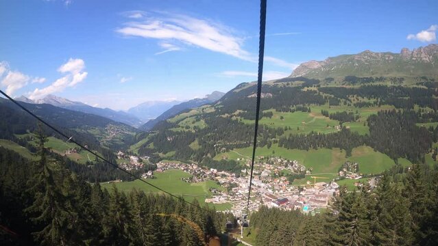 Cable car ride in canton Grisons Churwalden. The gondola lift descends into the valley. The small village in the valley can be seen.