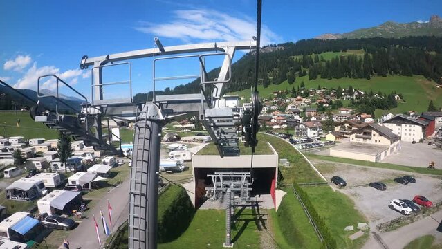 Cable car ride in Switzerland. The cable car descends into the valley. You can see the campsite in the village and the beautiful nature of Switzerland with its mountains. Grisons Churwalden