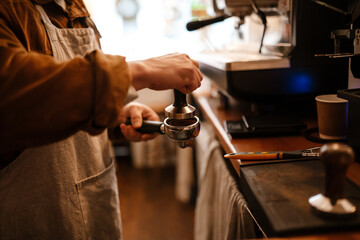 Fototapeta na wymiar Adult white man making coffee with machine while working in cafe
