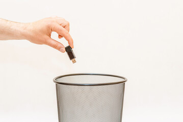 The Black USB memory device is thrown into the trash basket for disposal and recycling.White,gray background,selective focus,copy space.