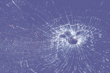 Bullet hole in a veri peri color glass on the purple,veri peri background.closeup.