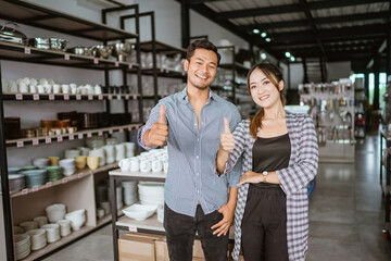 Asian man and woman standing with thumbs up at home appliance store