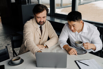 Adult serious multiracial businessmen working on laptop in office
