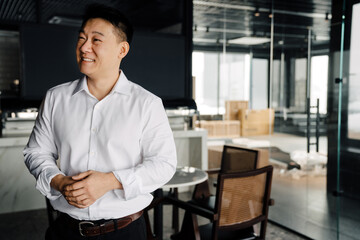 Adult asian businessman smiling and looking aside in office lobby