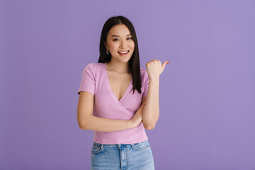 Asian young woman wearing t-shirt smiling and pointing finger aside
